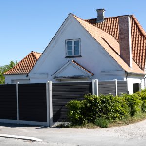 Komposithegn i mørkegrå med betonstolper i villahave