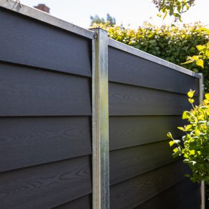 Komposithegn i mørkegrå med betonstolper i villahave