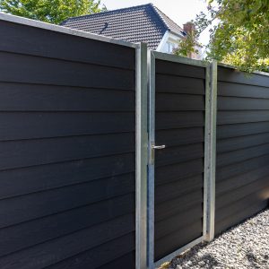 Komposithegn i mørkegrå med betonstolper i villahave